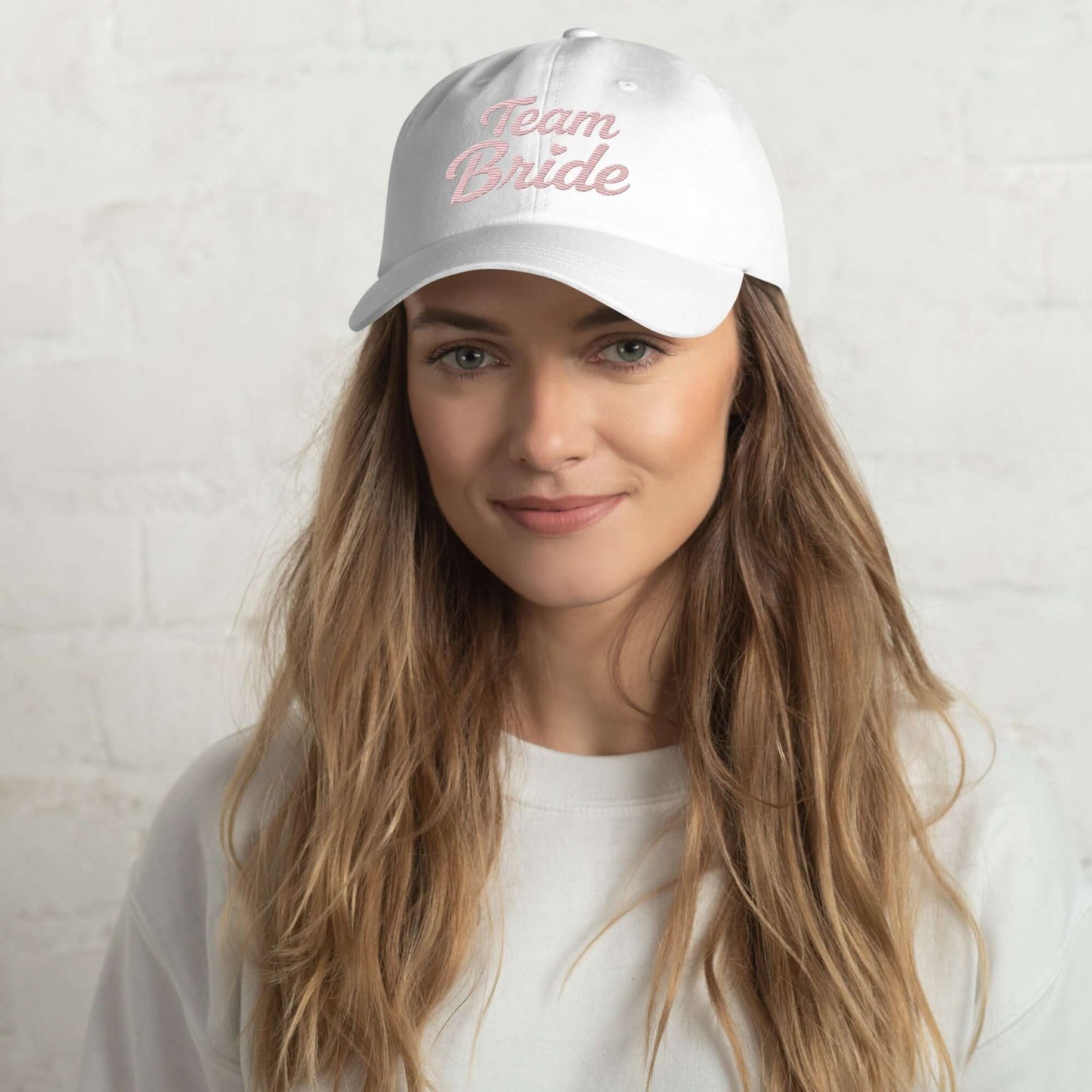 Cappellino bianco con ricamo rosa "Team Bride" indossato da giovane donna, perfetto per addio al nubilato.