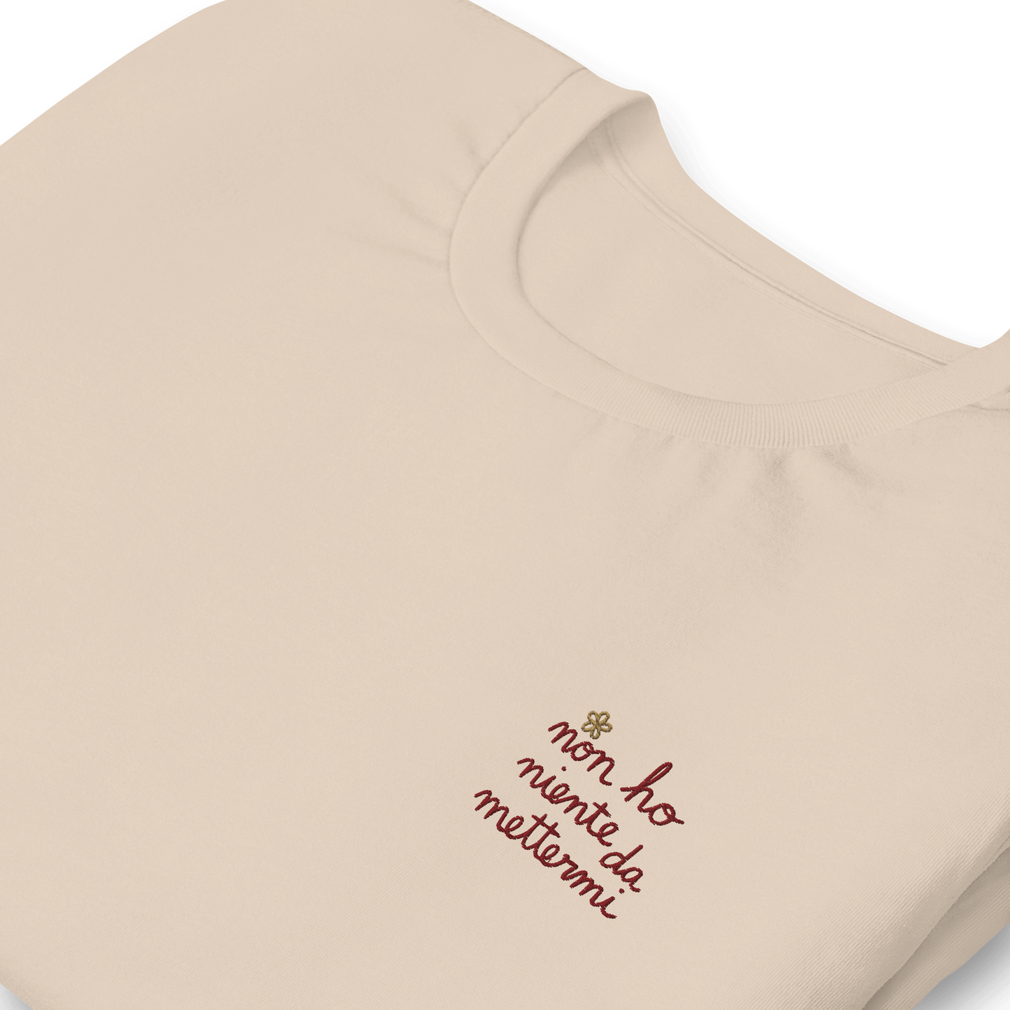 Maglietta ricamata da donna con la frase 'non ho niente da mettermi' su sfondo beige.