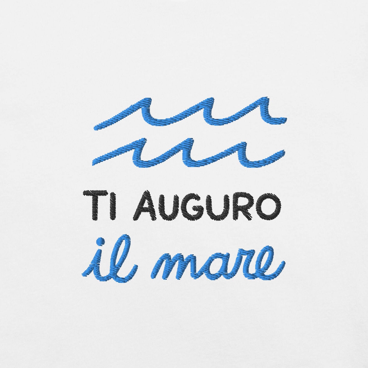 Ricamo della maglietta "Ti auguro il mare" con onde blu su sfondo bianco. Un messaggio poetico e significativo.