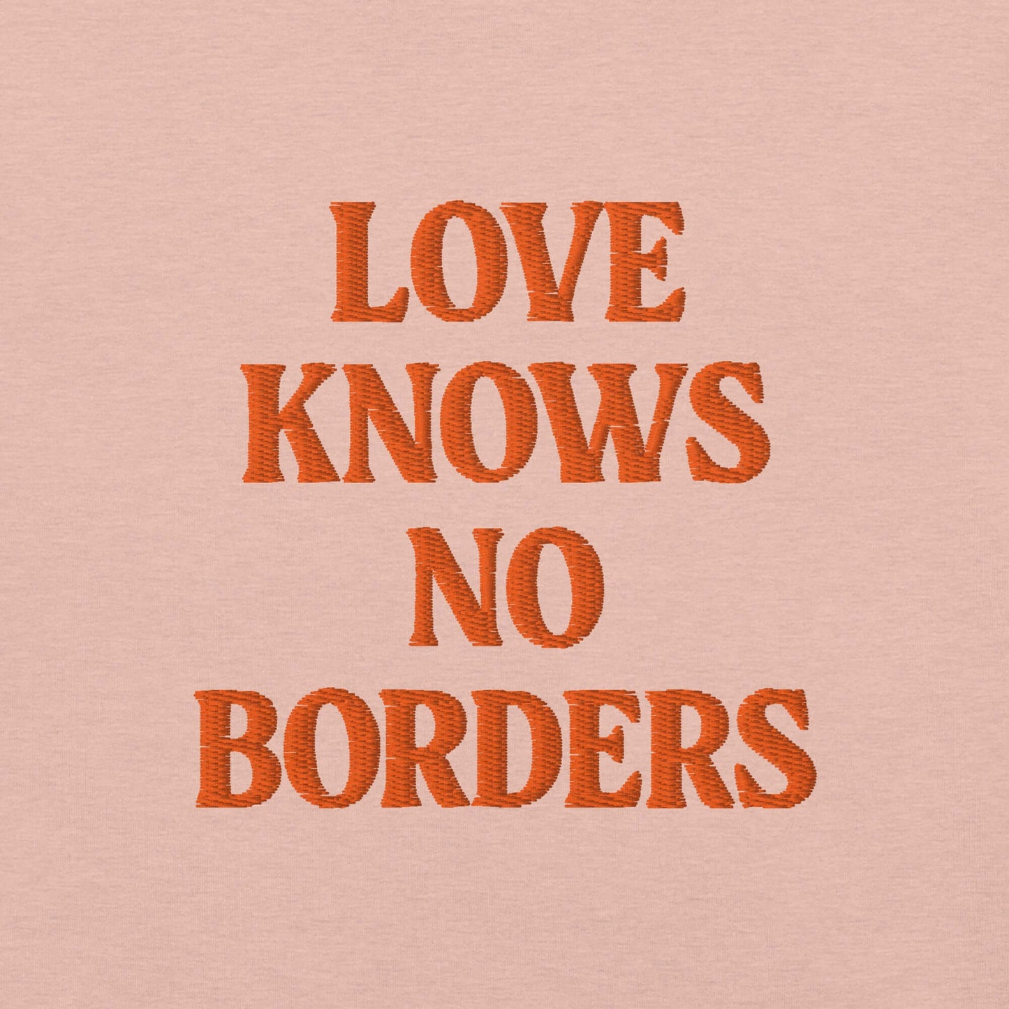 Ricamo su t-shirt Las Vegas con la frase 'Love Knows No Borders', in arancione su sfondo rosa.