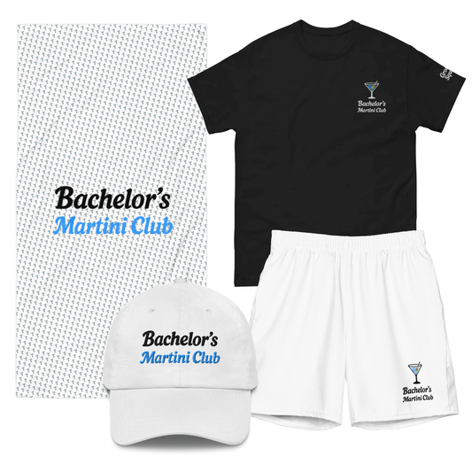 Set “Bachelor’s Martini Club” per addio al celibato estivo: t-shirt nera con logo cocktail, costume bianco coordinato, cappellino ricamato e telo con pattern martini e scritta.