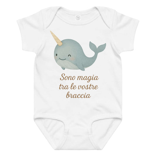Vista frontale del body neonato bianco con illustrazione di un narvalo e scritta “Sono magia tra le vostre braccia” sul petto.