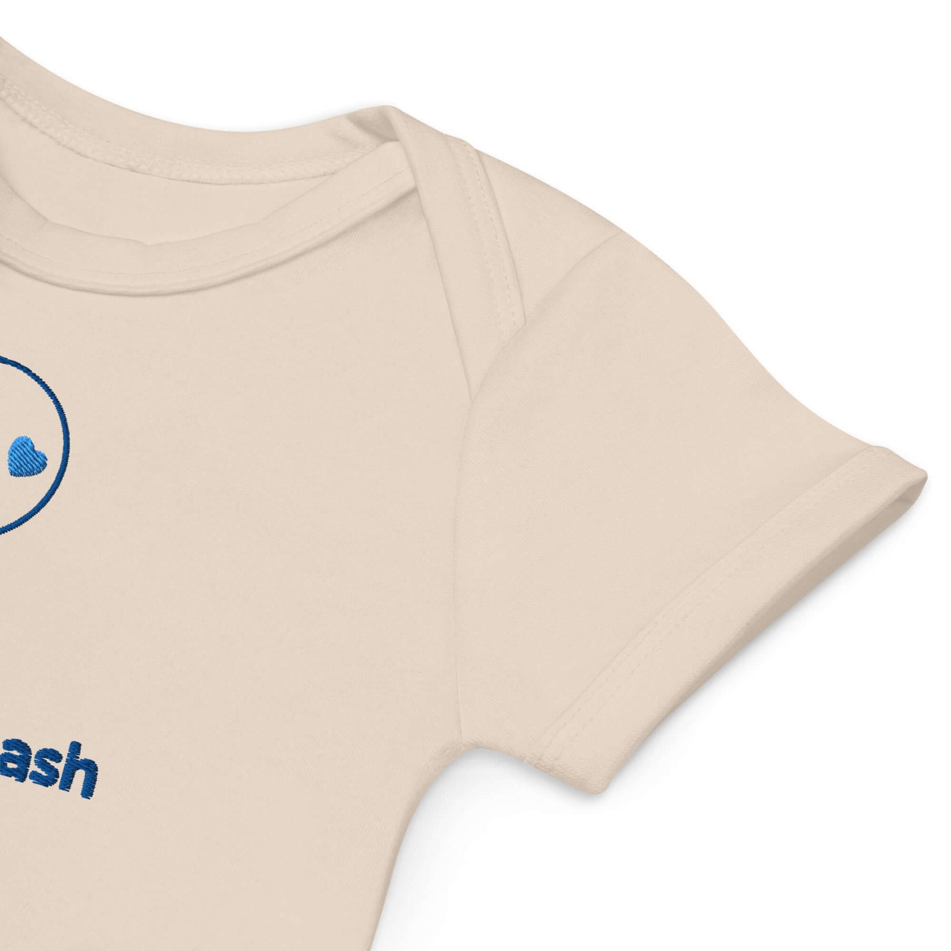 Dettaglio di un body neonato personalizzato in cotone organico con ricamo per bimbo, colore beige.