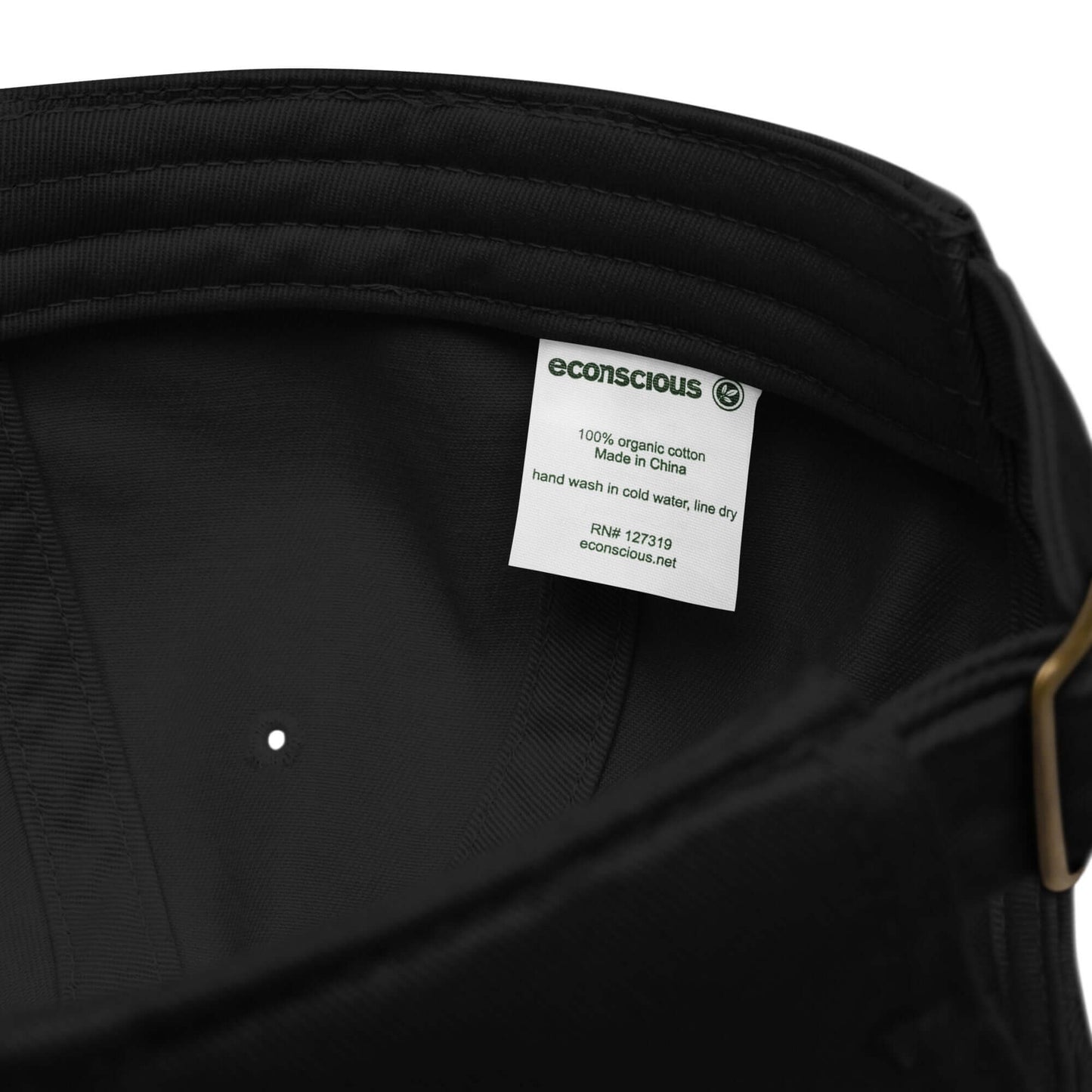 Interno del cappellino ricamato in tessuto organico, etichetta e dettagli di cura.