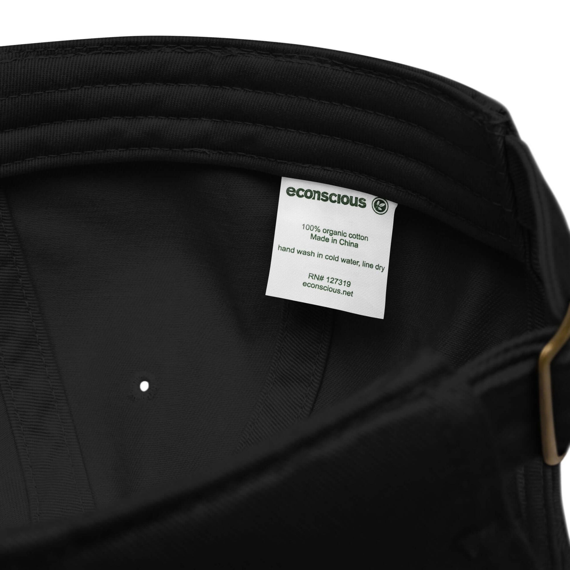 Interno del cappellino ricamato in tessuto organico, etichetta e dettagli di cura.