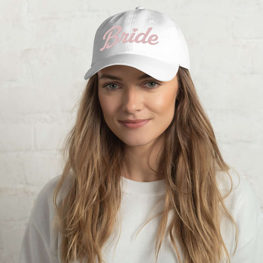 Cappellino sposa bianco con ricamo rosa "Bride", indossato da una giovane donna.