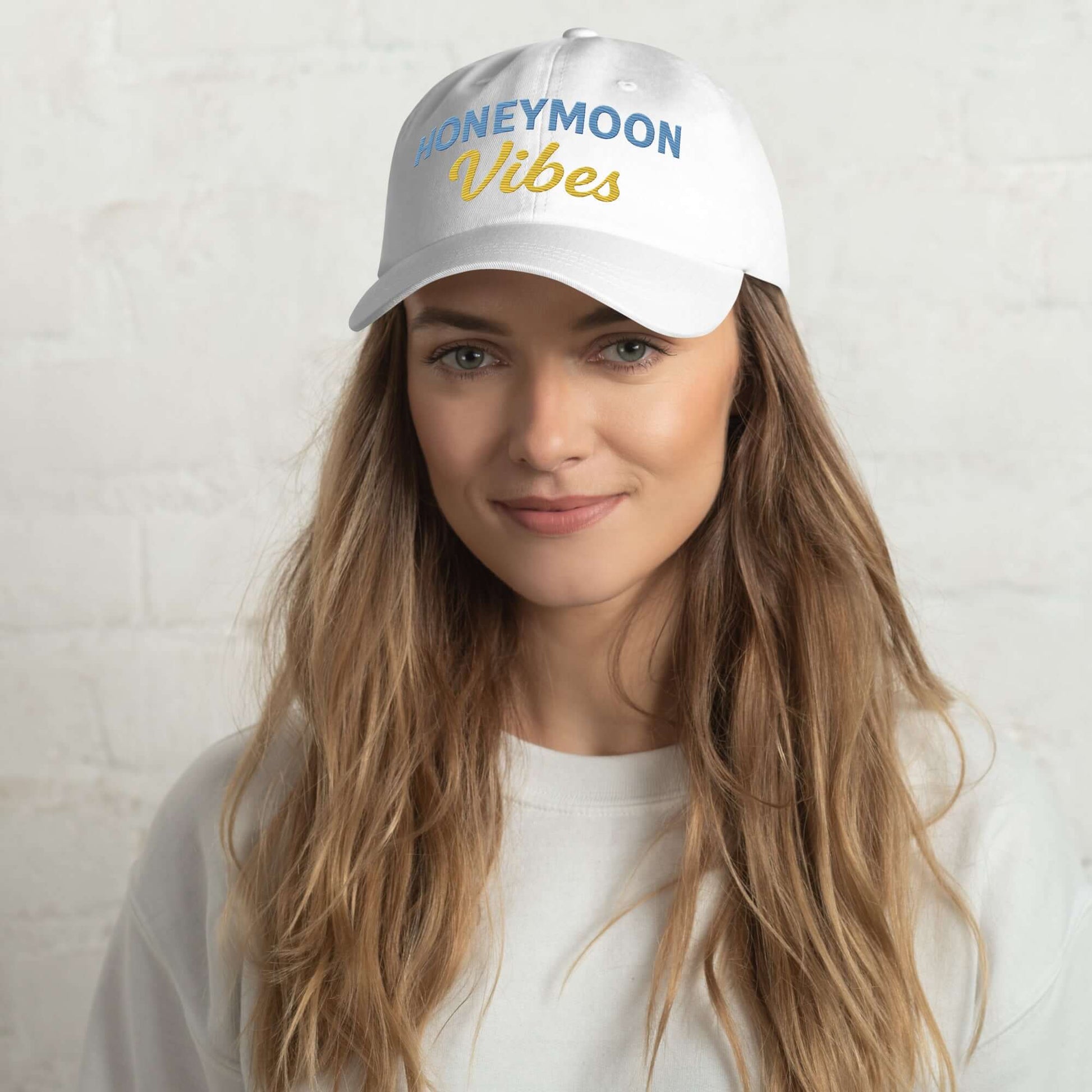 Cappellino unisex bianco ricamato "HONEYMOON Vibes" indossato da giovane, ideale per look romantici e casual.