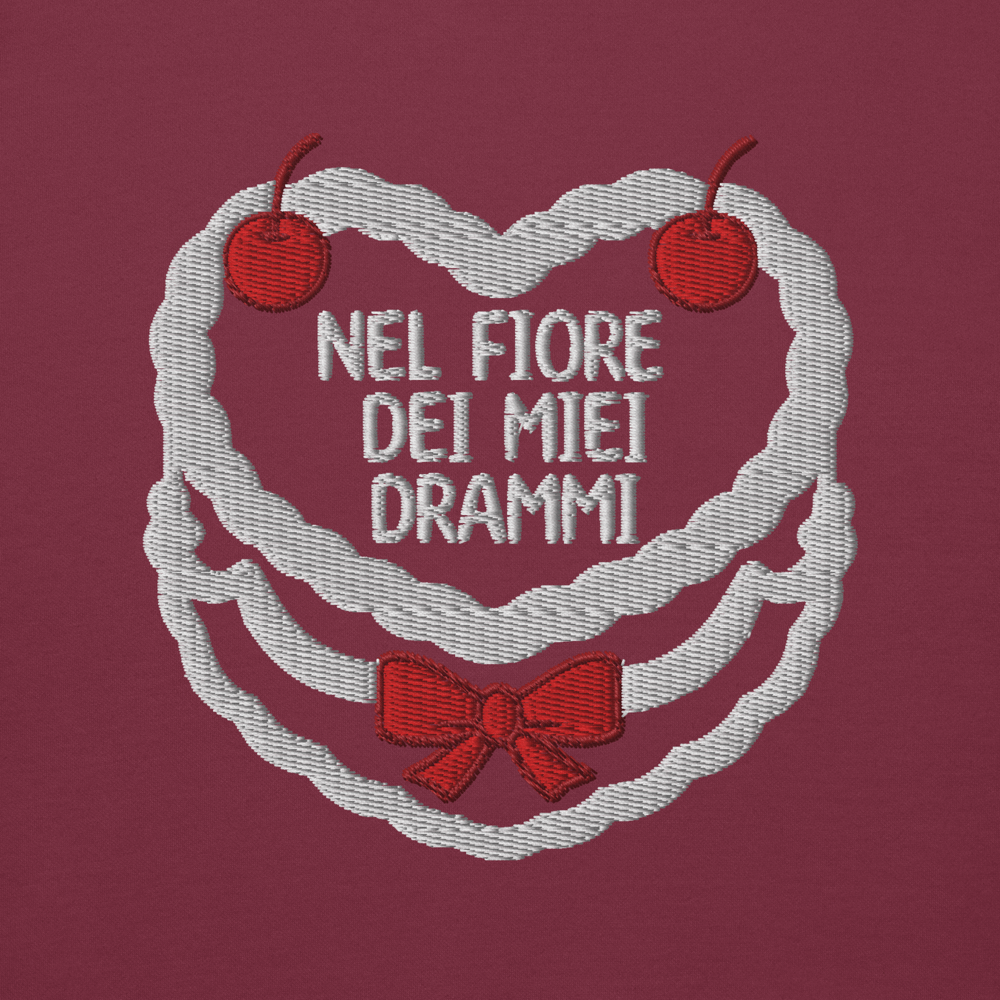 Ricamo 'Nel fiore dei miei drammi' su felpa color prugna, con cuori e ciliegie decorative.