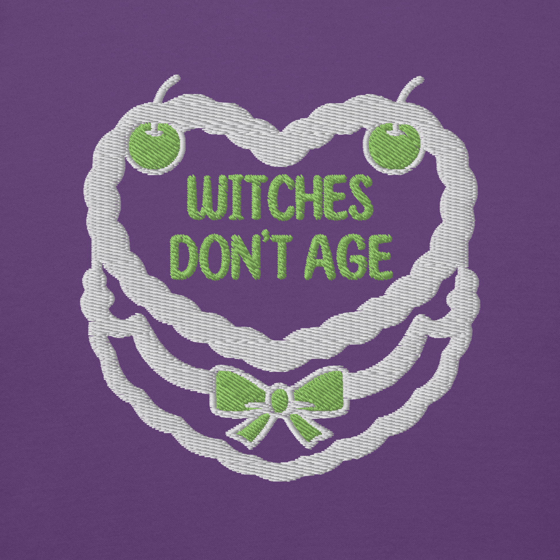 Ricamo felpa compleanno 'Witches don't age' su sfondo viola, design divertente e dark.