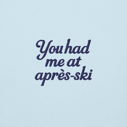 Scritta ricamata su felpa azzurra: "You had me at après-ski" in stile elegante e divertente.