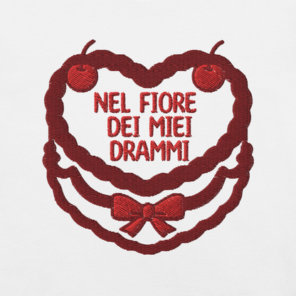 Ricamo t-shirt con scritta 'Nel fiore dei miei drammi' su sfondo bianco, dettagli in rosso.