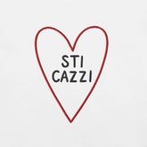 Ricamo cuori con scritta 'STI CAZZI' su maglietta bianca, stile ironico e casual per donne.