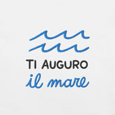 Ricamo della maglietta "Ti auguro il mare" con onde blu su sfondo bianco. Un messaggio poetico e significativo.