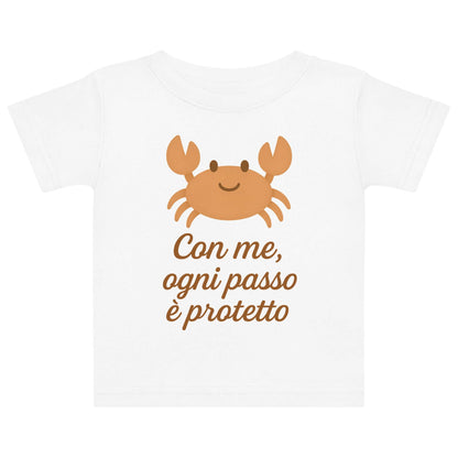 Vista frontale della t-shirt neonato bianca con illustrazione di un granchio e scritta “Con me, ogni passo è protetto” sul petto.