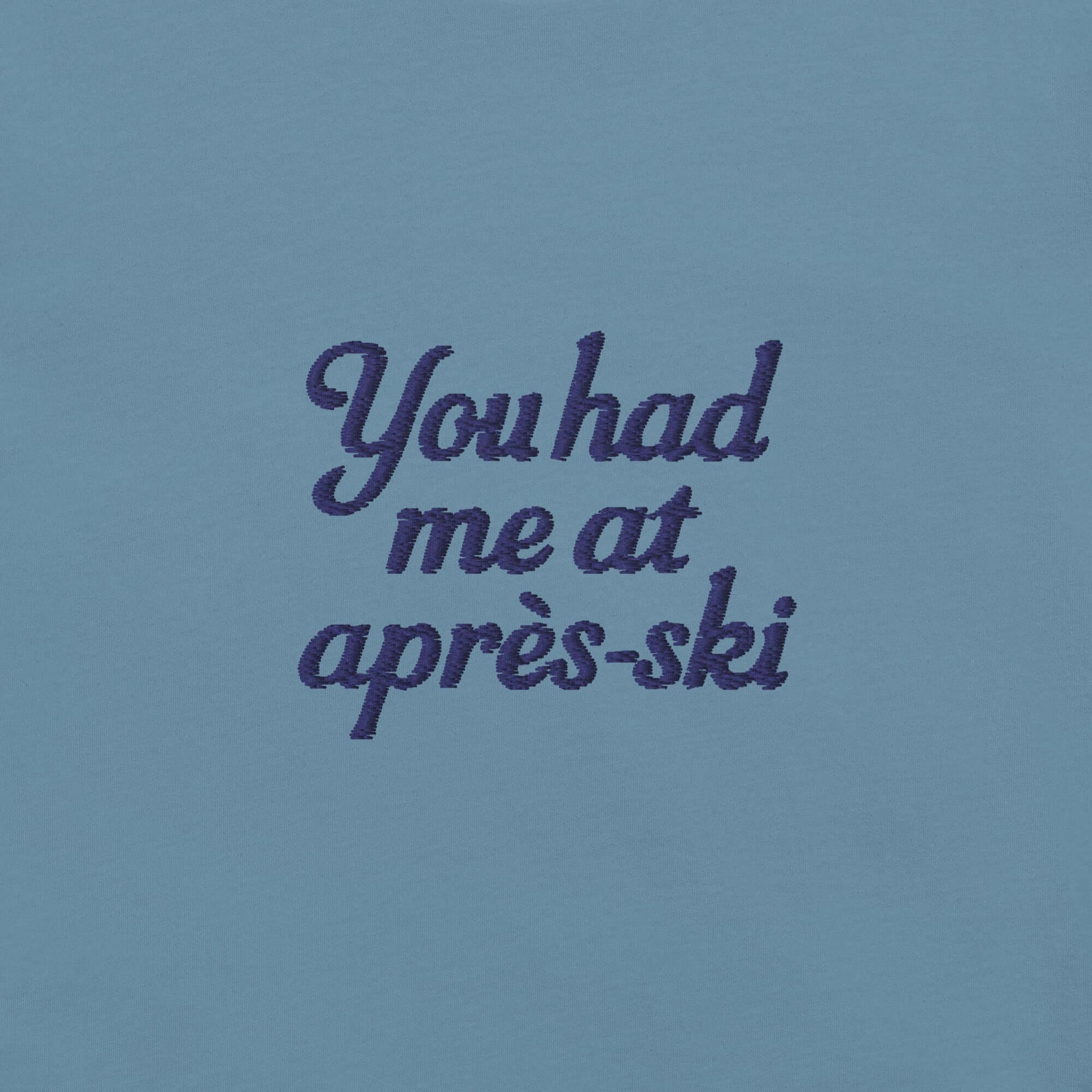 T-shirt uomo con ricamo 'You had me at aprés-ski' in blu su sfondo celeste, perfetta per appassionati di montagna.