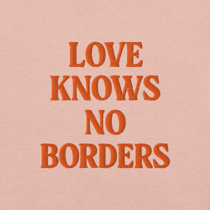 Ricamo su t-shirt Las Vegas con la frase 'Love Knows No Borders', in arancione su sfondo rosa.