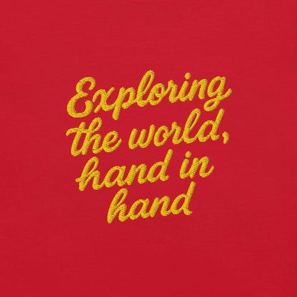 T-shirt giapponese da donna con frase ricamata "Exploring the world, hand in hand" su sfondo rosso.